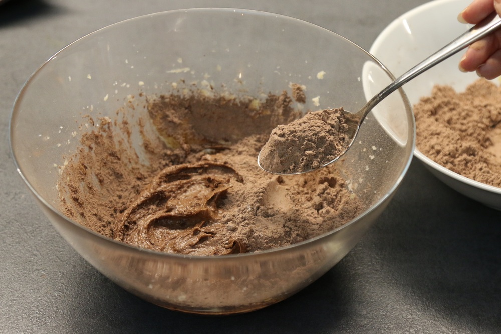 Pakāpeniski miltu un kakao maisījumu iejauc pirmās bļodas saturā. Sākumā var maisīt ar karoti vai mi