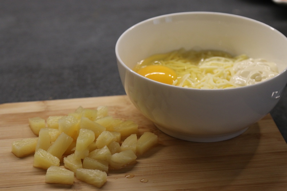 Bļodiņā liek sarīvētu sieru, olu, majonēzi un mazos gabaliņos sagrieztus ananasus, pievieno arī garš
